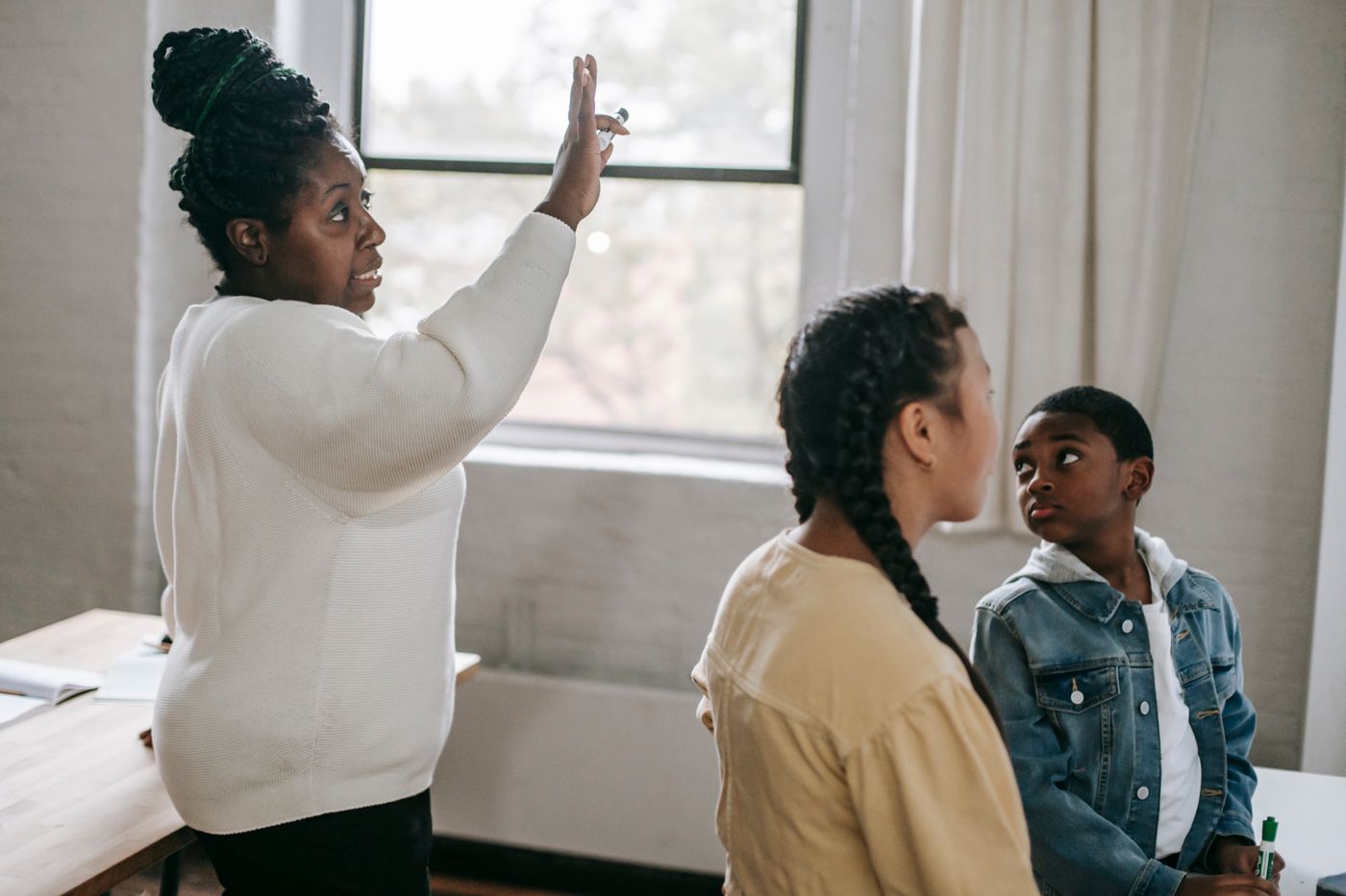 A teacher talking with two students in a classroom.