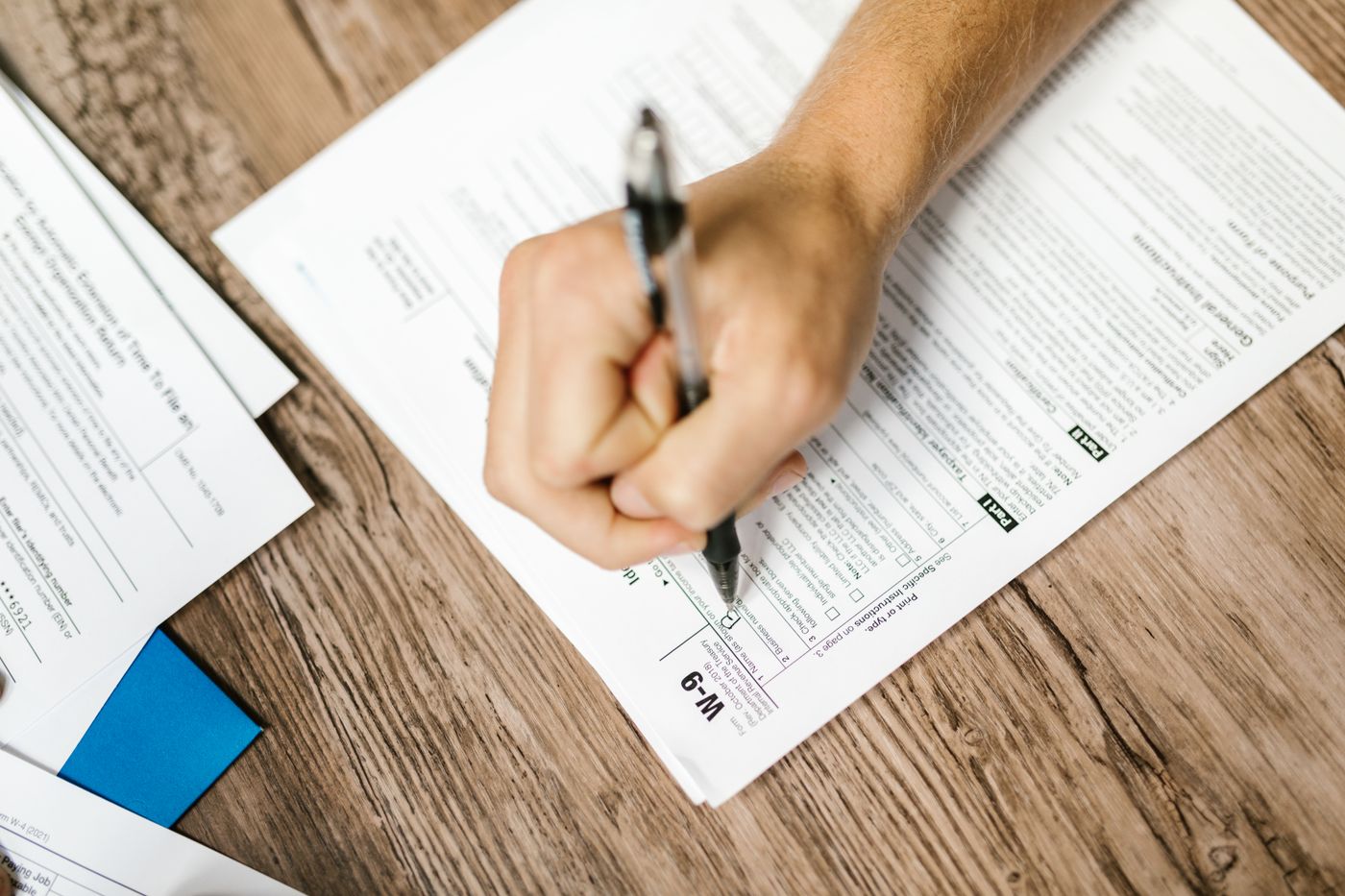 A hand filling out a paper form with a pen.
