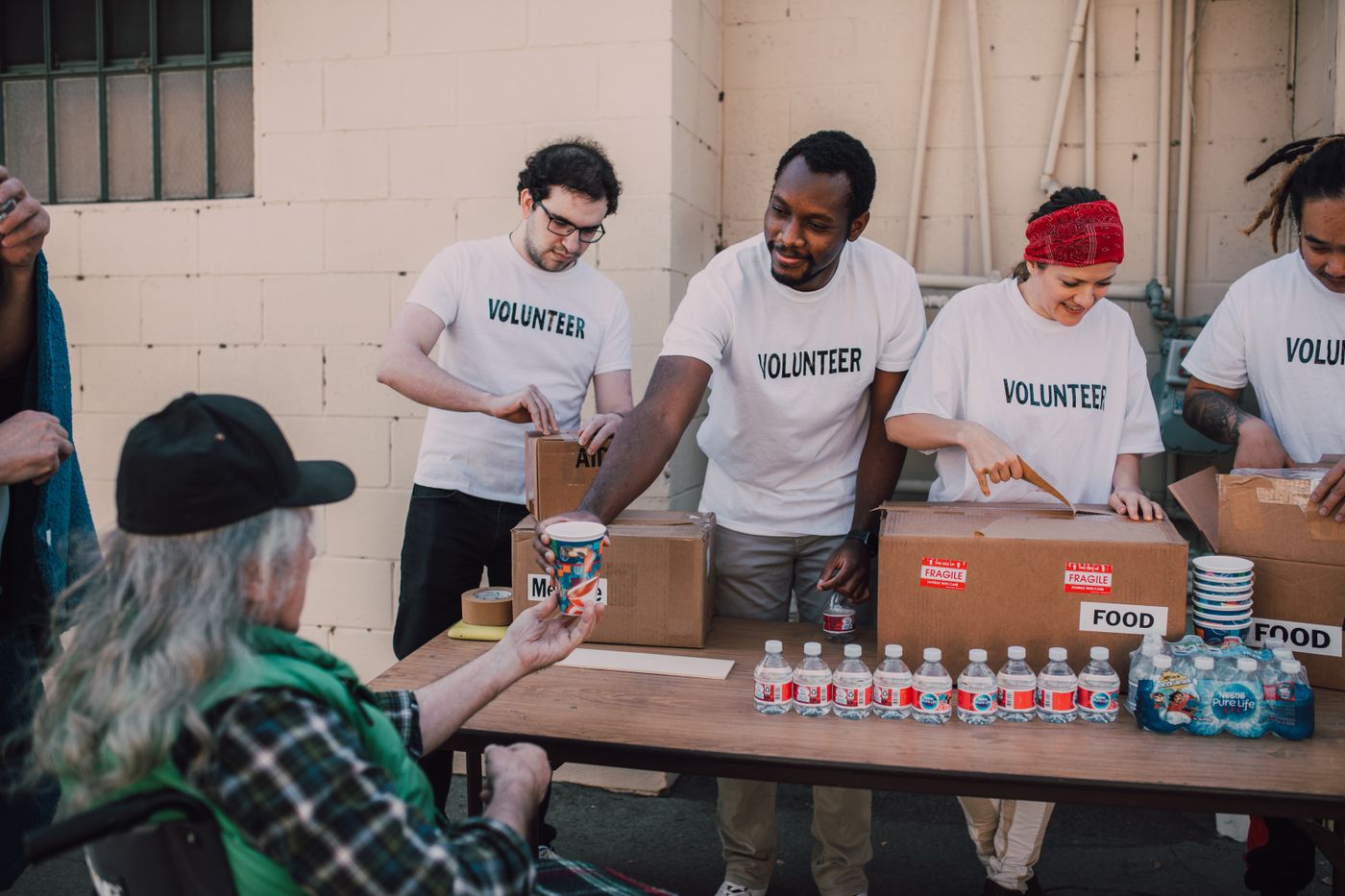 Volunteers handing out food and water at an outdoor table.
