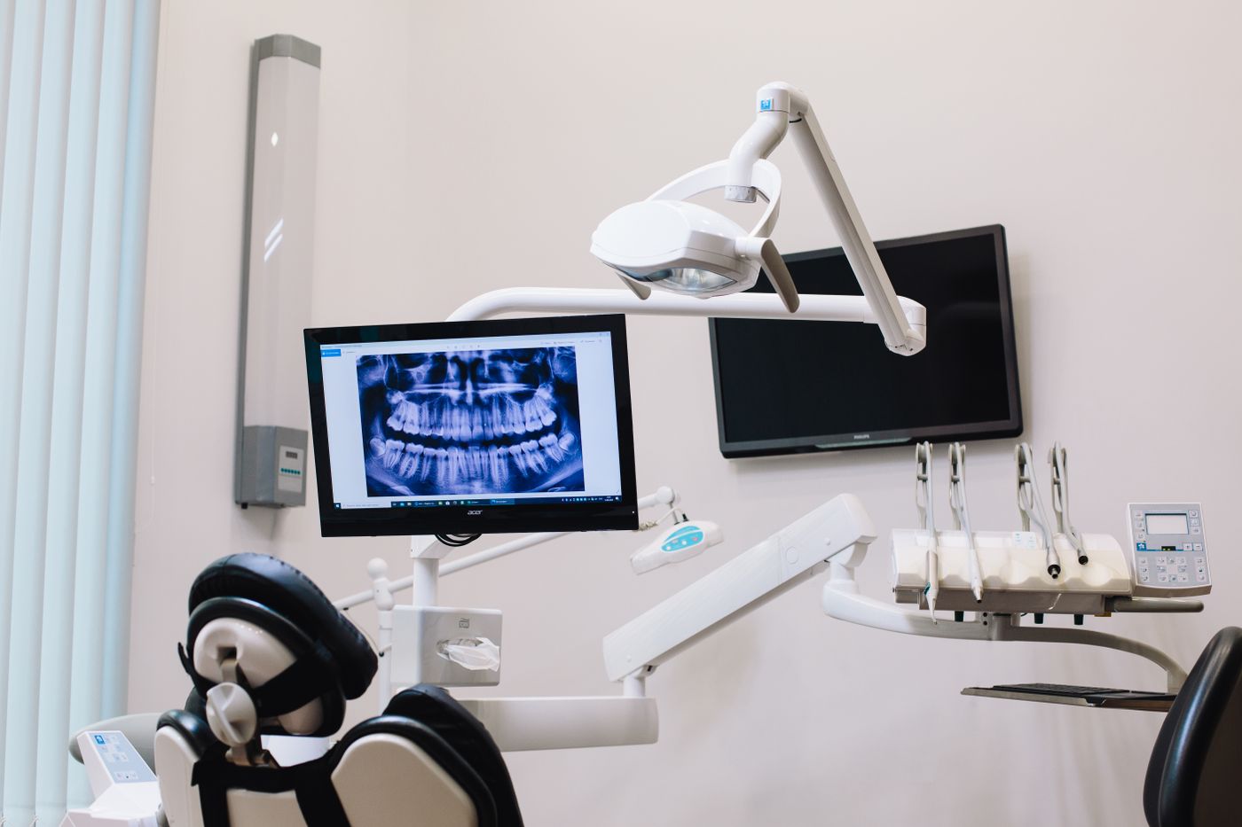 A dental treatment room with a chair and an X-ray on a monitor.